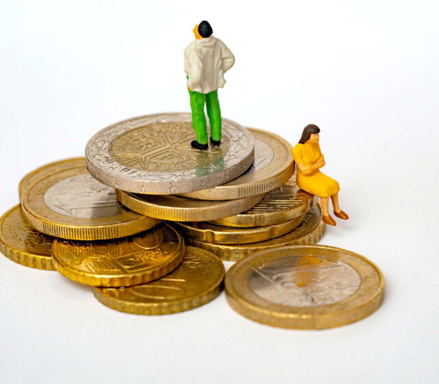 Symbolbild Gehaltsverhandlungen - zwei sehr kleines Menschen sitzt auf einem Stapel Euro-Münzen und streiten sich